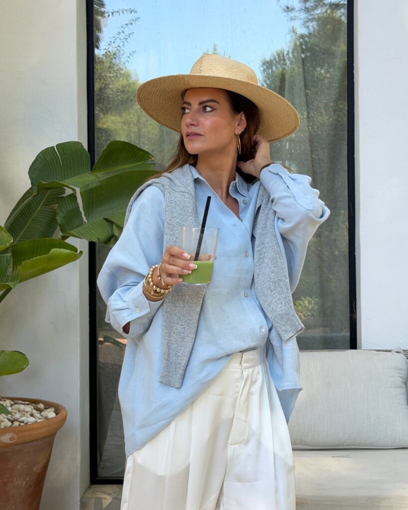Danielle de Ridder in een lichtblauwe linnen blouse en strohoed op Ibiza